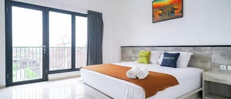 A hotel room with a large bed, a painting on the wall, and a balcony with a view.