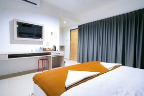 Una habitación de hotel con cama, escritorio, silla y ventana.