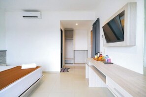 Una habitación de hotel moderna con una cama, un televisor montado en la pared, una mesita de noche de madera y un armario empotrado.
