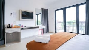 Habitación de hotel con cama, escritorio, silla, televisor y balcón con vistas.