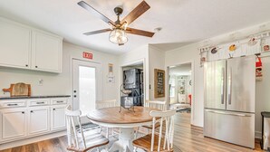 Una cocina moderna con armarios blancos, una mesa de comedor de madera y un refrigerador de acero inoxidable.