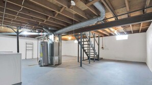Een industrieel interieur met zichtbare balken, een boiler en een metalen trap.