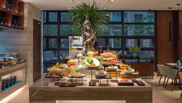 A buffet setup with various dishes and a decorative plant centerpiece. - SSAW Boutique Hotel Shanghai South Xuhui (Shanghai)