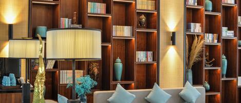 A well-lit living room with a sofa, lamps, and a bookshelf filled with books and decorative items.
