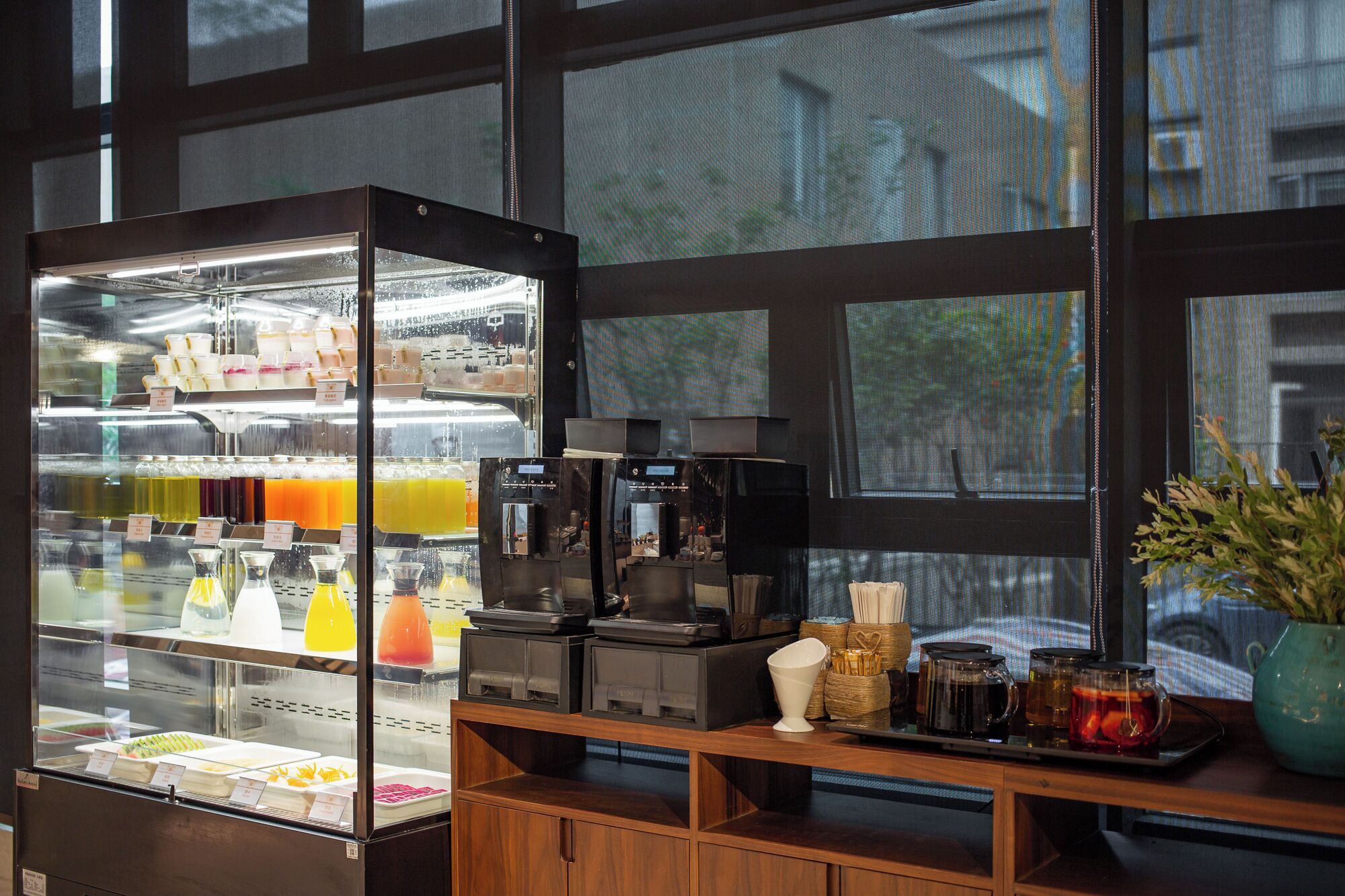 A café with a glass display case filled with beverages and a coffee machine.