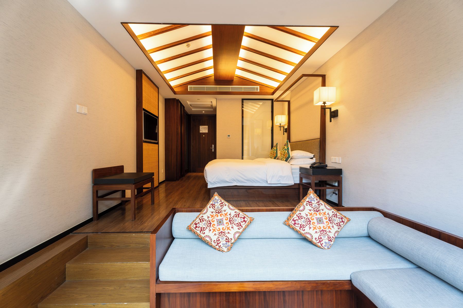 A hotel room with a sofa, a bed, a desk, and a staircase.