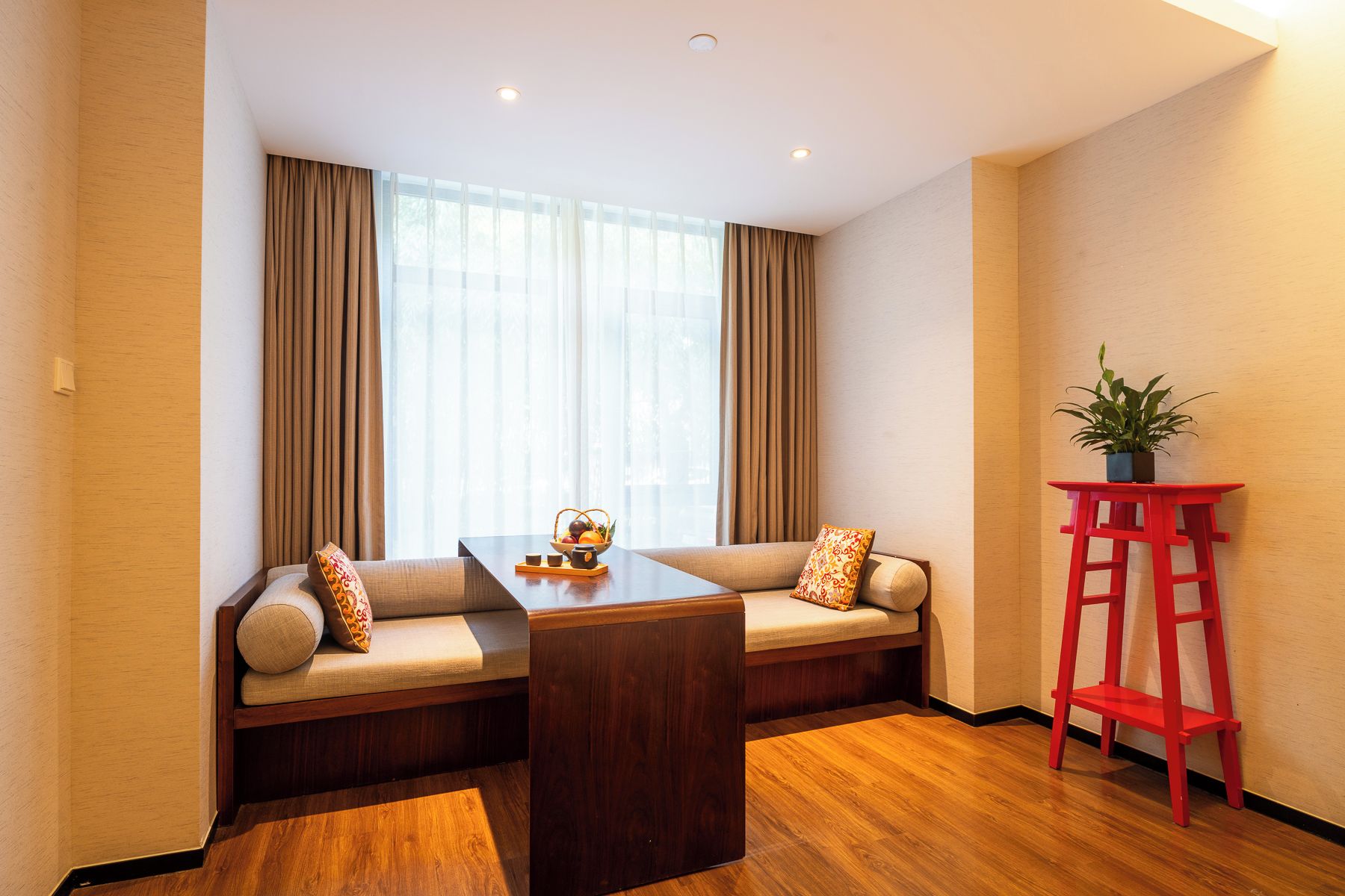 Una sala de estar moderna con un conjunto de sofás, una mesa de centro de madera y una silla roja.