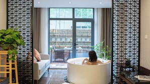 A modern bathroom with a freestanding bathtub, a sofa, and a view of a bamboo fence and outdoor seating area. - SSAW Boutique Hotel Shanghai South Xuhui (Shanghai)