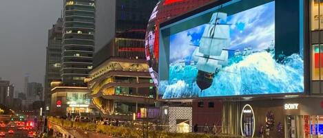 A modern urban area with a large digital billboard displaying a ship.