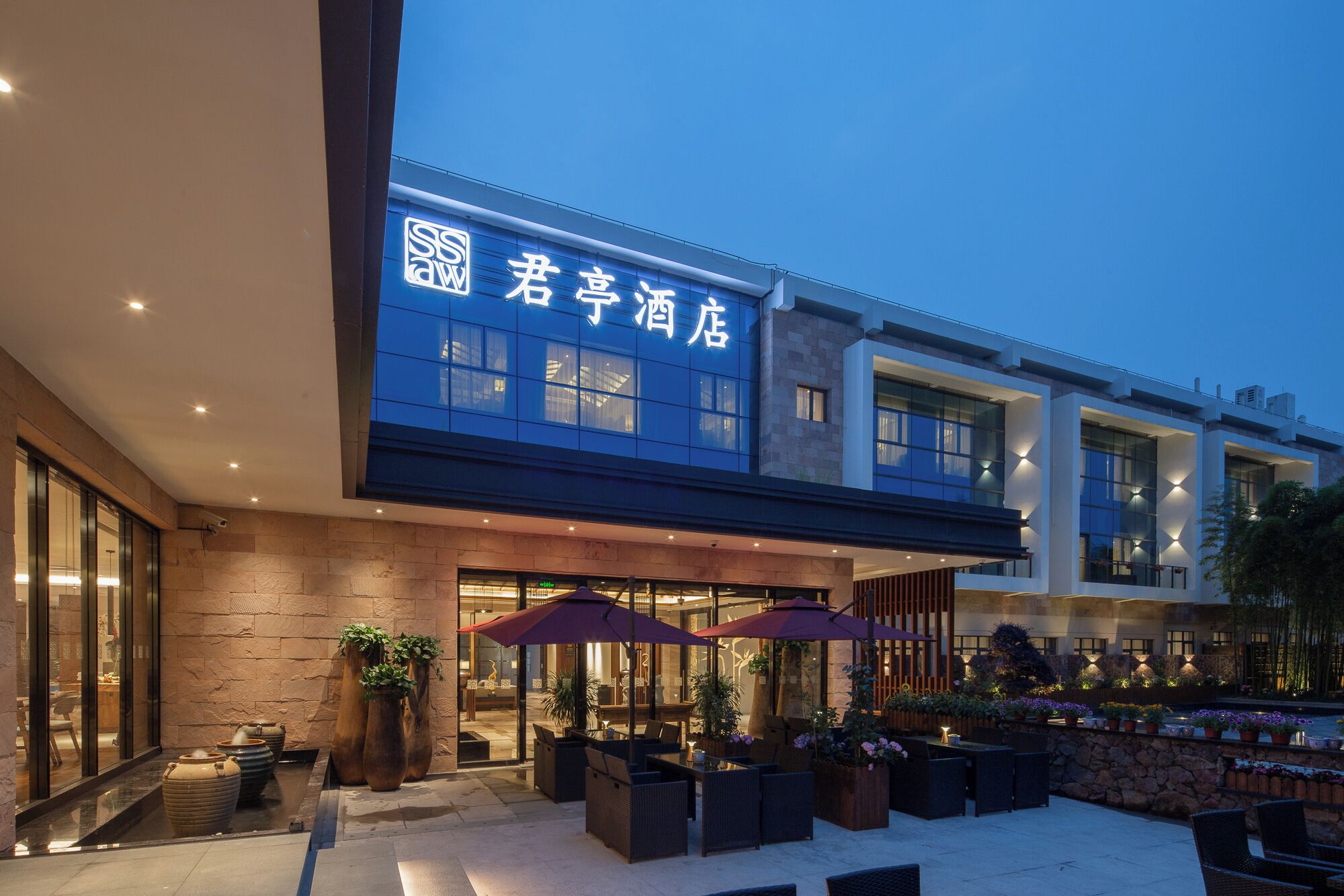 Een hotel met een moderne gevel, een terras buiten en een duidelijke ingang.