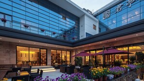 A modern hotel with a glass facade, outdoor seating area, and potted plants. - SSAW Boutique Hotel Shanghai South Xuhui (Shanghai)
