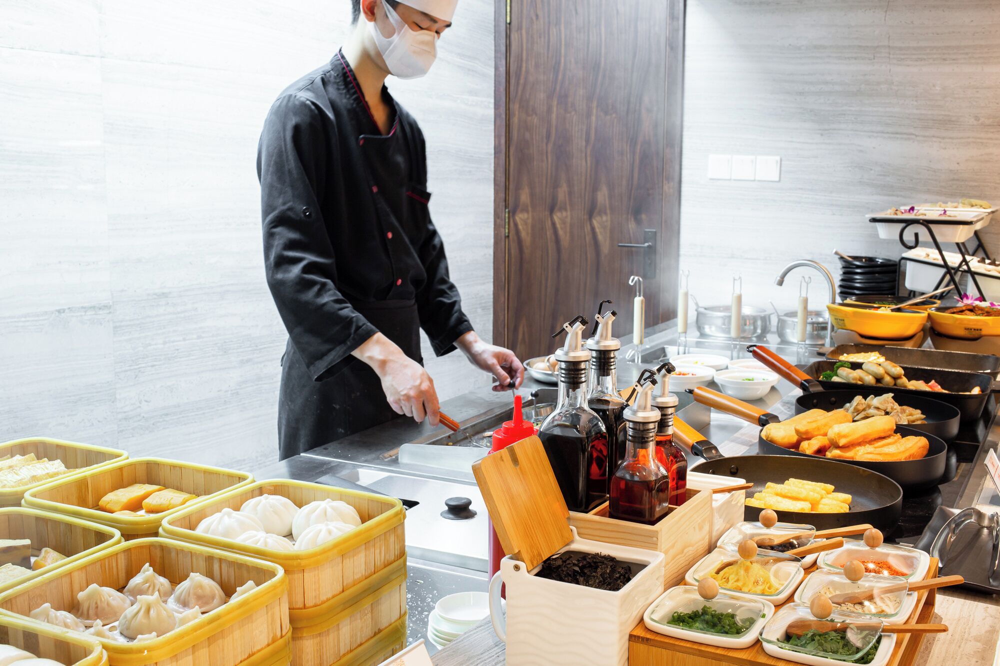 Un chef préparant des plats dans une cuisine, avec différents mets et condiments à disposition.