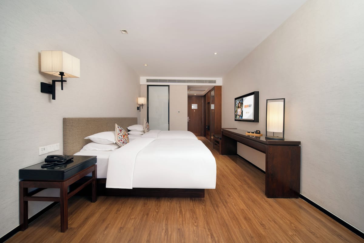 Une chambre d’hôtel comprenant un lit, une table de chevet, une lampe et un bureau avec une chaise.