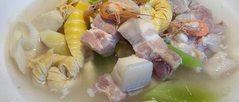 A bowl of soup with various seafood and vegetables.