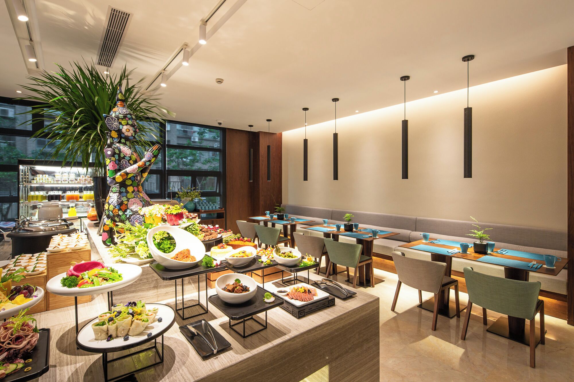 Montaje de bufé con diversas opciones de comida y una planta decorativa.