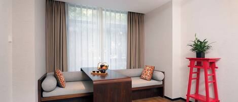 A modern living room with a sofa, a wooden coffee table, and a red side table with a plant.
