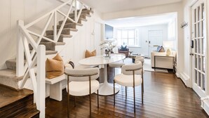 Un salon moderne avec un escalier, une table de salle à manger ronde et des sièges.