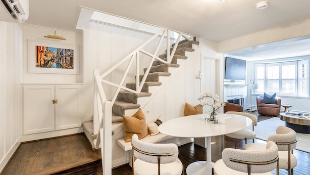 Un salon moderne avec un escalier blanc, une table à manger ronde et un coin salon confortable.