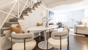Un salon moderne avec un escalier, une table de salle à manger ronde et deux fauteuils.