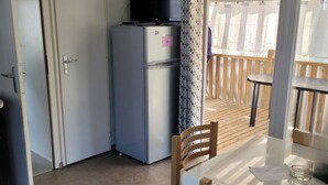 Eine kompakte Küche mit Kühlschrank, Mikrowelle und Esstisch mit Stühlen.
