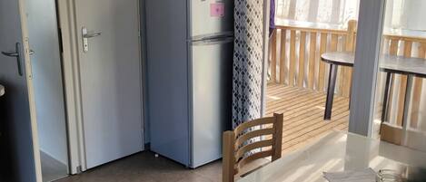 Una cocina compacta con refrigerador, microondas y una mesa de comedor con sillas.