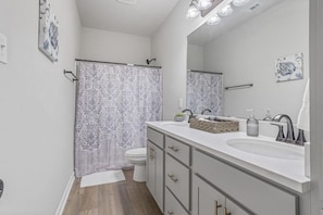 Une salle de bain moderne avec un meuble-lavabo à deux vasques, une douche avec un rideau à motifs et des toilettes.