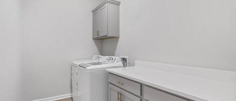 A laundry room with a washing machine, a dryer, and a countertop.