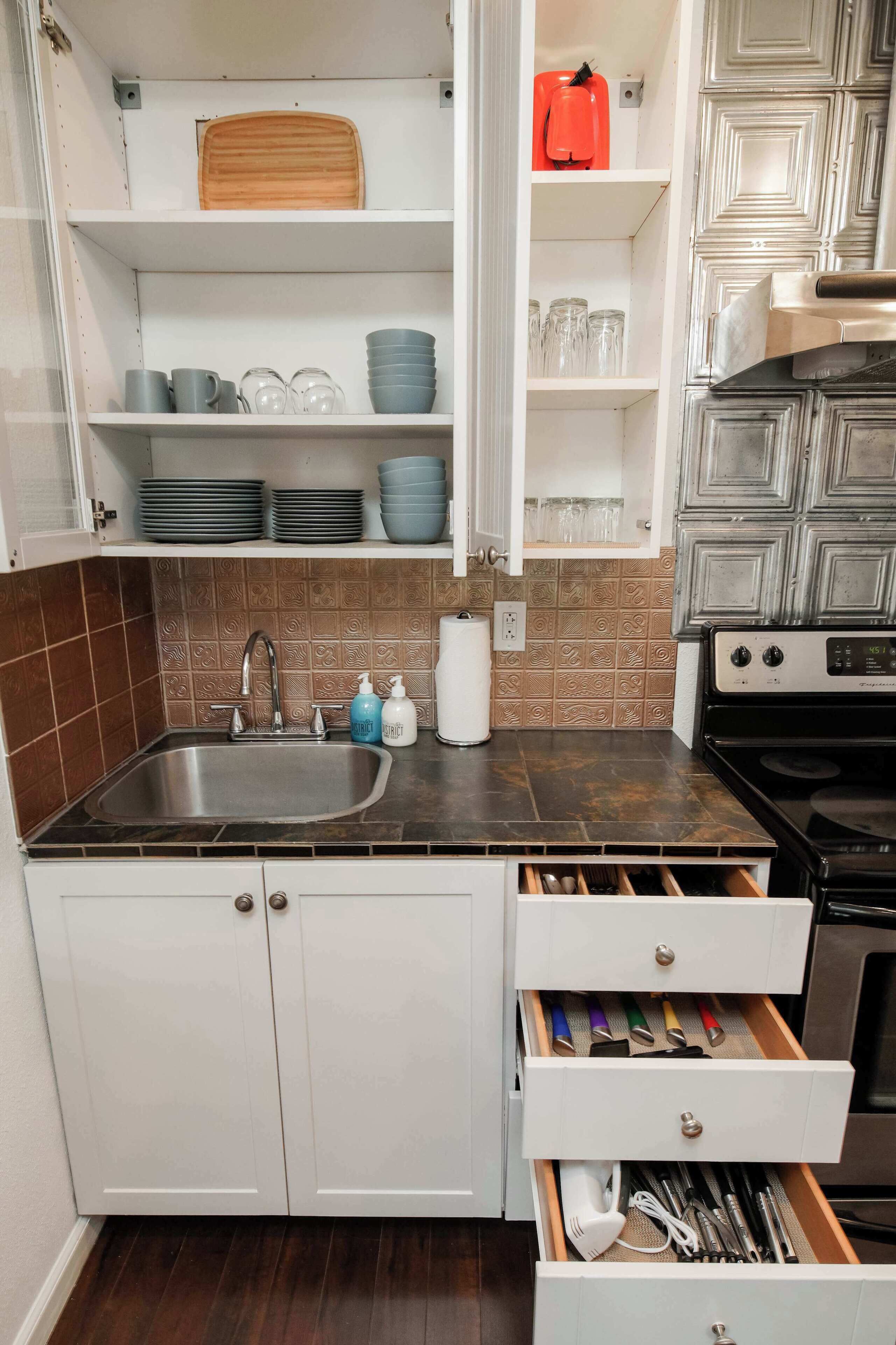Een keuken met een spoelbak, kastjes en een fornuis.
