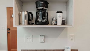 Une cuisine équipée d’une machine à café, d’une bouilloire et de récipients de rangement sur le plan de travail.