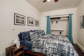 A bedroom with a bed, a nightstand with a lamp, a towel rack, and three framed pictures on the wall. - #StayinMyDistrict Kenton Private Guest House (Portland)