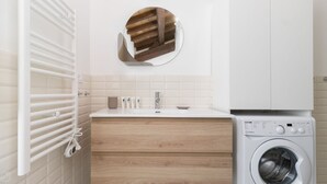 A modern bathroom with a wooden vanity, a built-in washing machine, and a towel rack. - Rome  City Center, close to Trevi Fountain! Enjoy the Eternal City!  (Roma)