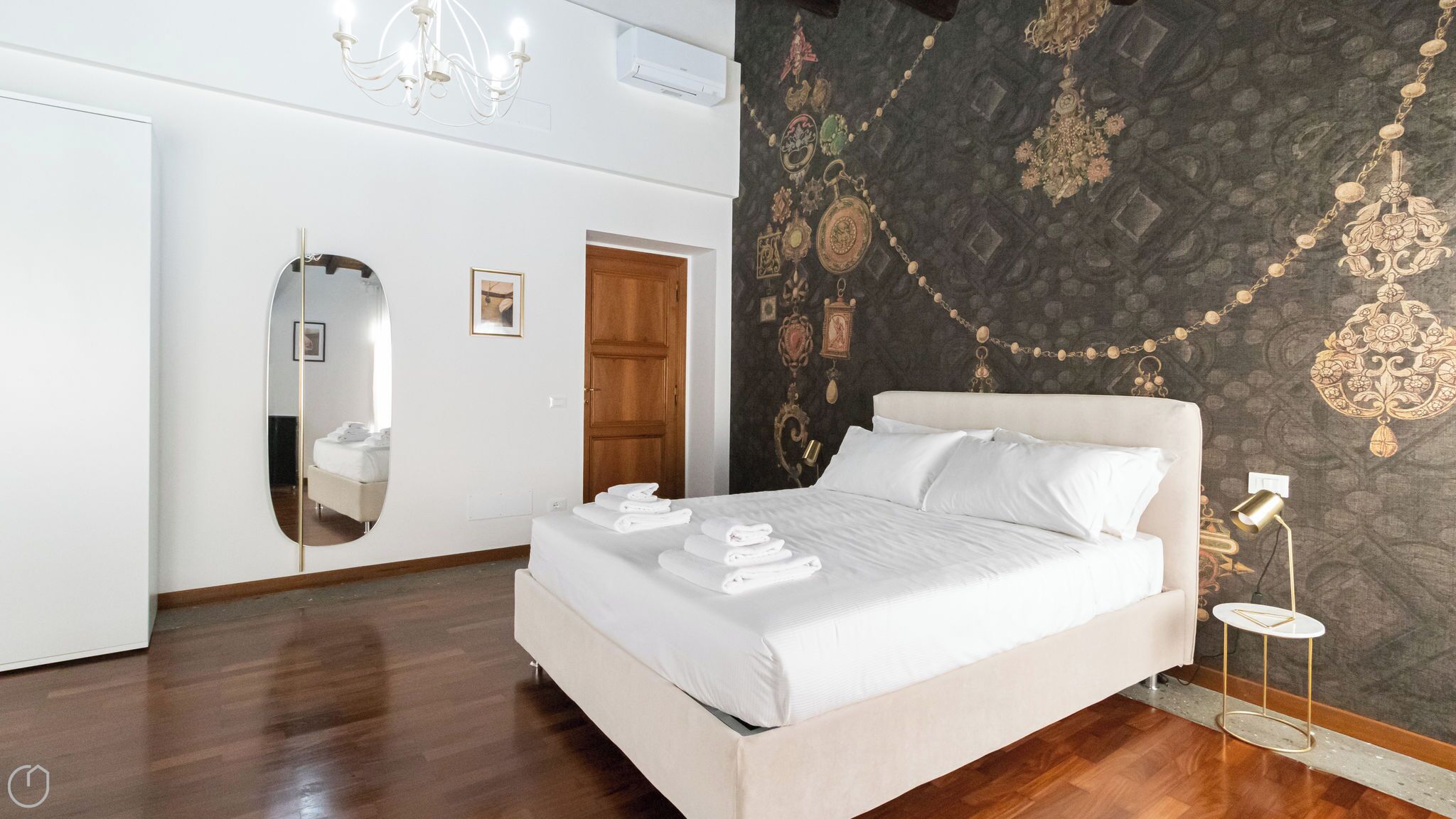 Ein Hotelzimmer mit einem großen Bett, einem Spiegel, einer Kandelaber und einer Wandverzierung.