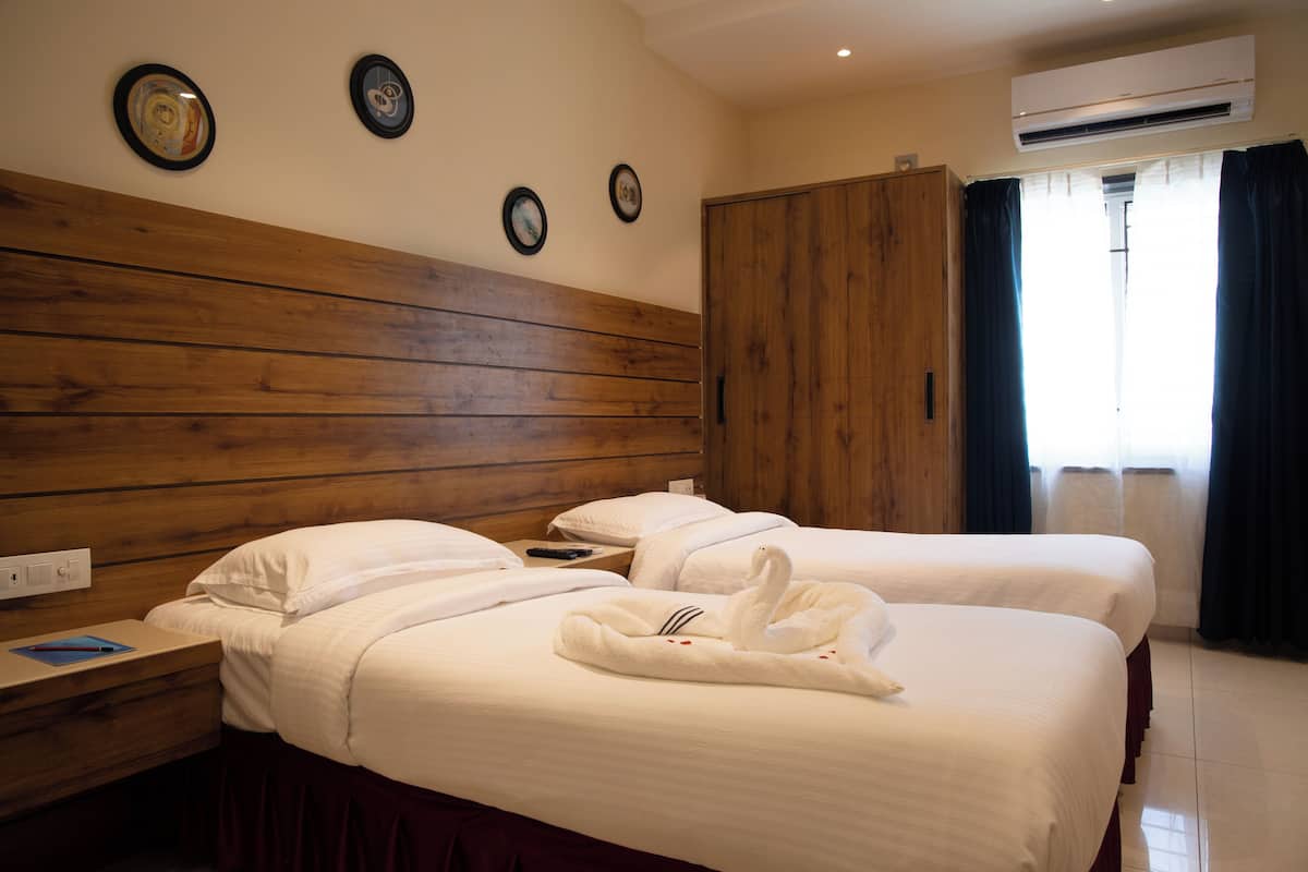 A hotel room with two beds, wooden headboard, bedside tables, and a wardrobe.