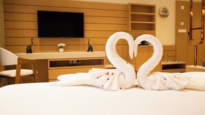 Una habitación de hotel con cama, escritorio, televisión y espejo.