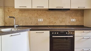 A kitchen with white cabinets, a double sink, a stove, and an oven.