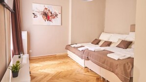 A modern bedroom with a bed, a painting on the wall, and a potted plant.