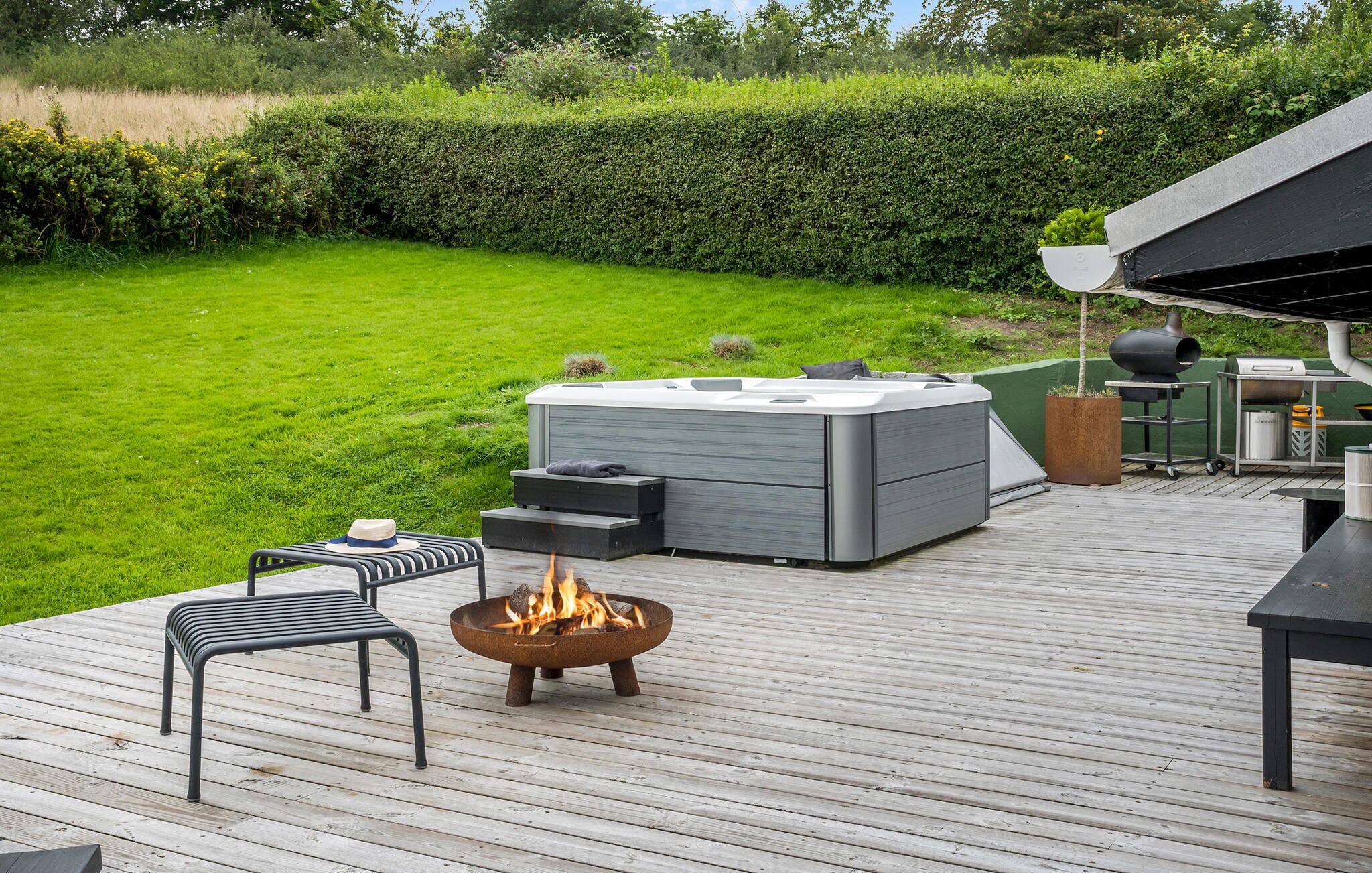 A deck with a hot tub, a fire pit, and outdoor furniture.