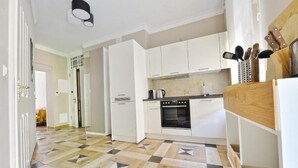 A modern kitchen with white cabinets, a black oven, and a patterned floor.