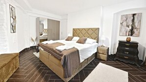 A modern bedroom with a large bed, a dresser, and a mirror.