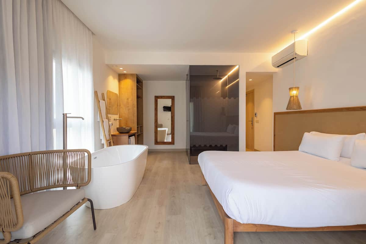Een moderne hotelkamer met een groot bed, een badkuip, een zithoek en een douche.