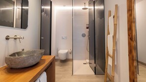A modern bathroom with a stone sink, toilet, and glass shower enclosure. - Play Hotel Ibiza (Ibiza Town)
