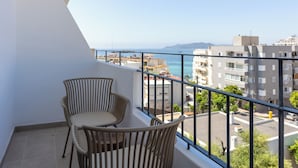 A balcony with two wicker chairs, a view of the sea, and buildings in the background. - Play Hotel Ibiza (Ibiza Town)