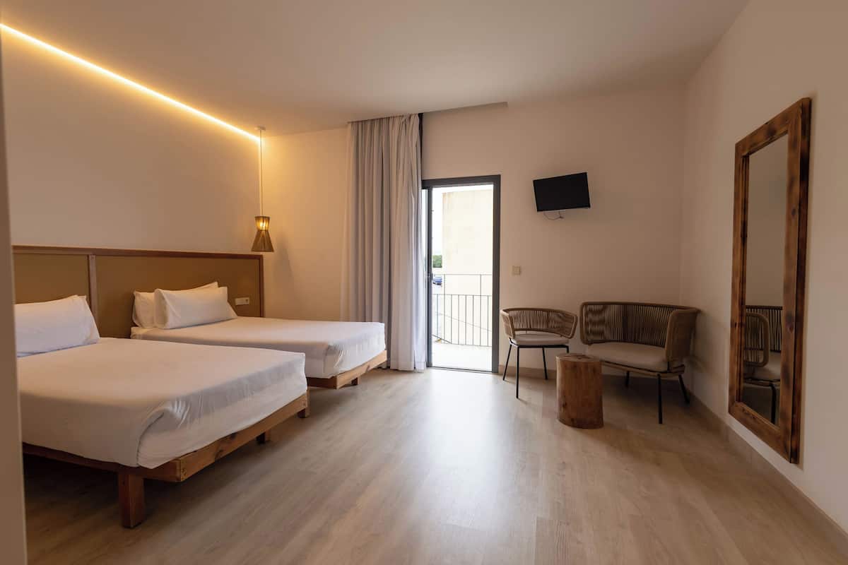Een hotelkamer met twee bedden, een bank, een stoel, een klein houten tafeltje en een televisie aan de muur.