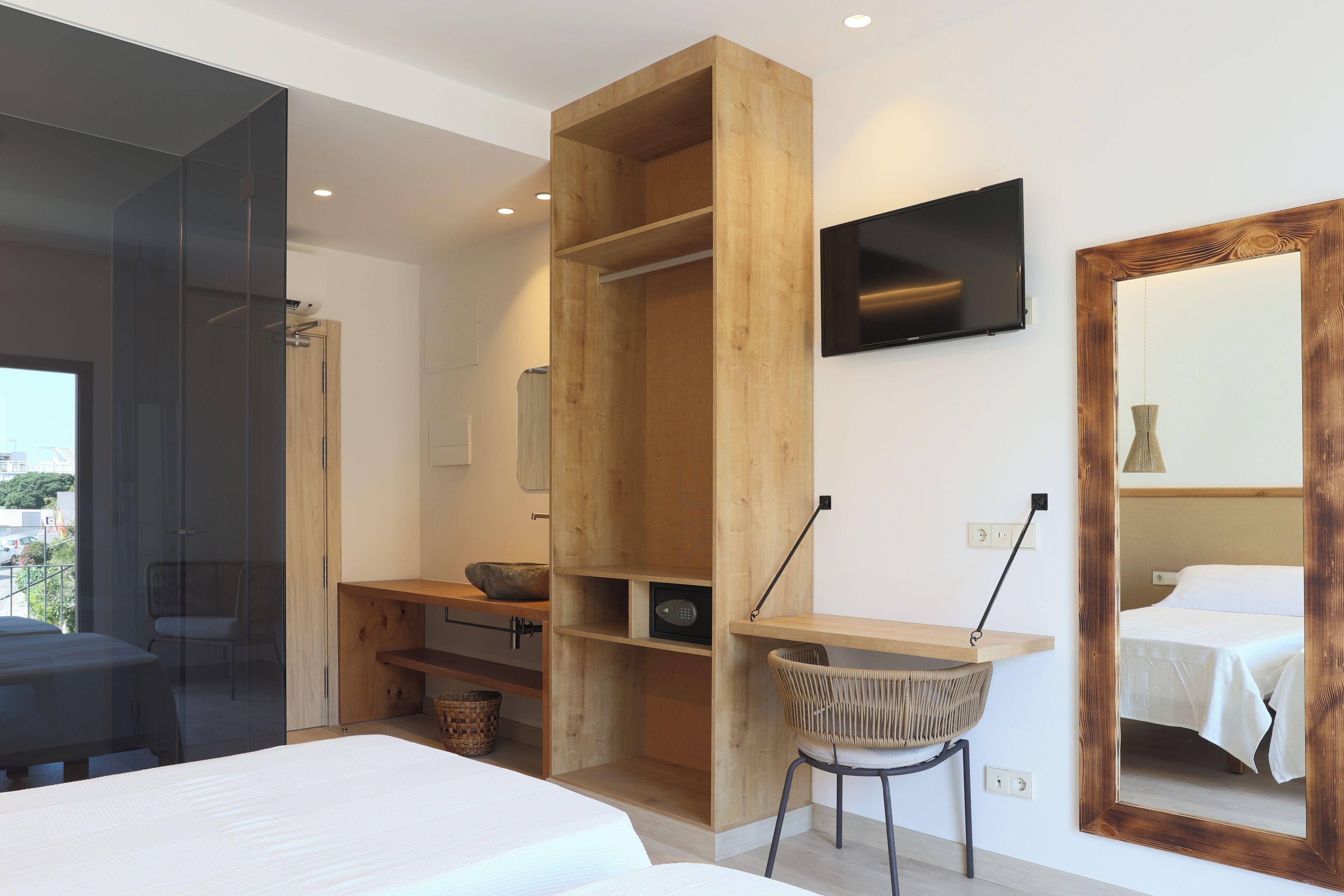 Una camera da letto moderna con un'armadio in legno, una scrivania con una sedia, un letto e una TV a parete.