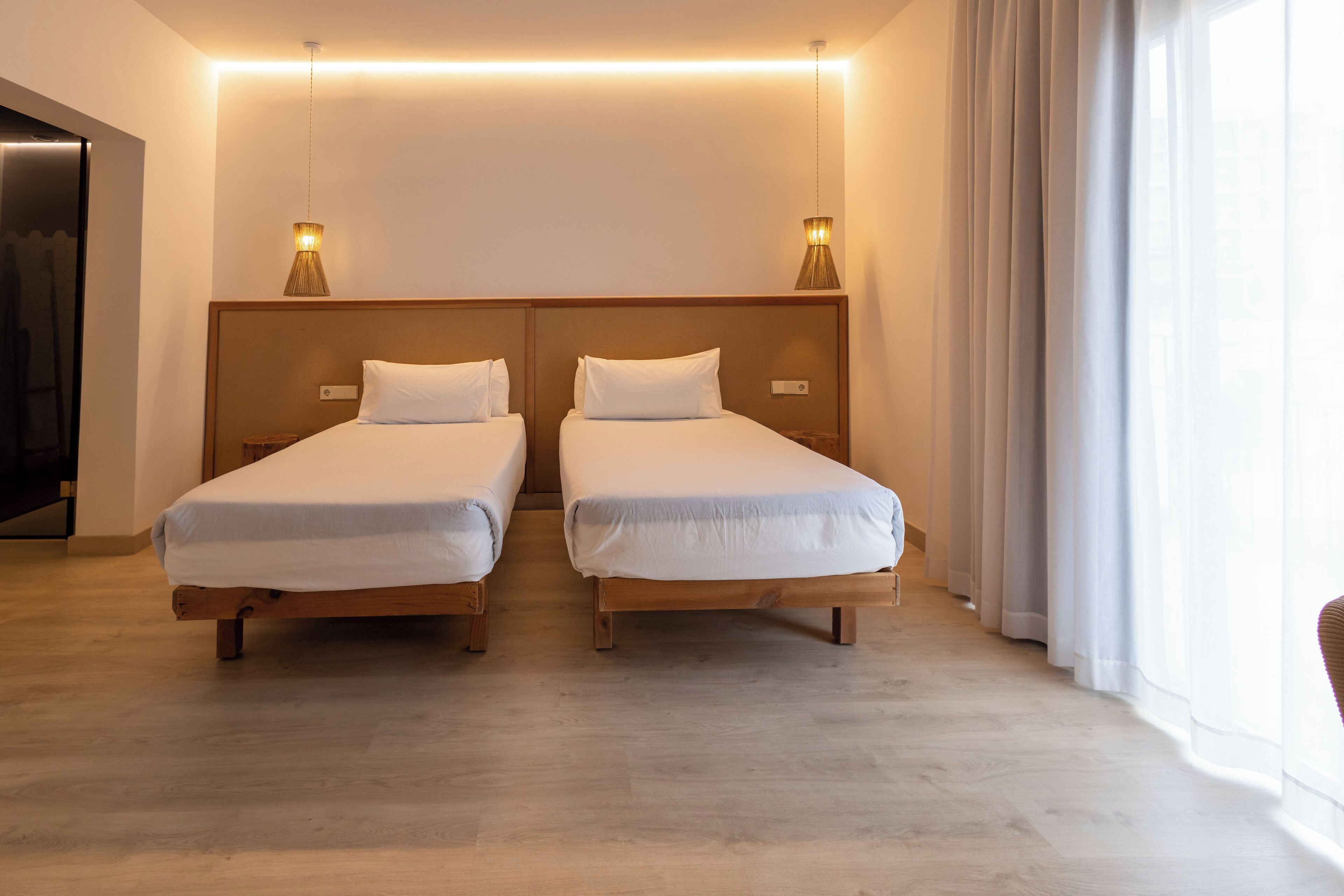 A hotel room with two single beds, wooden headboards, and bedside lamps.