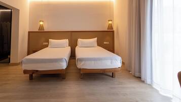 A hotel room with two single beds, wooden headboards, and bedside lamps.