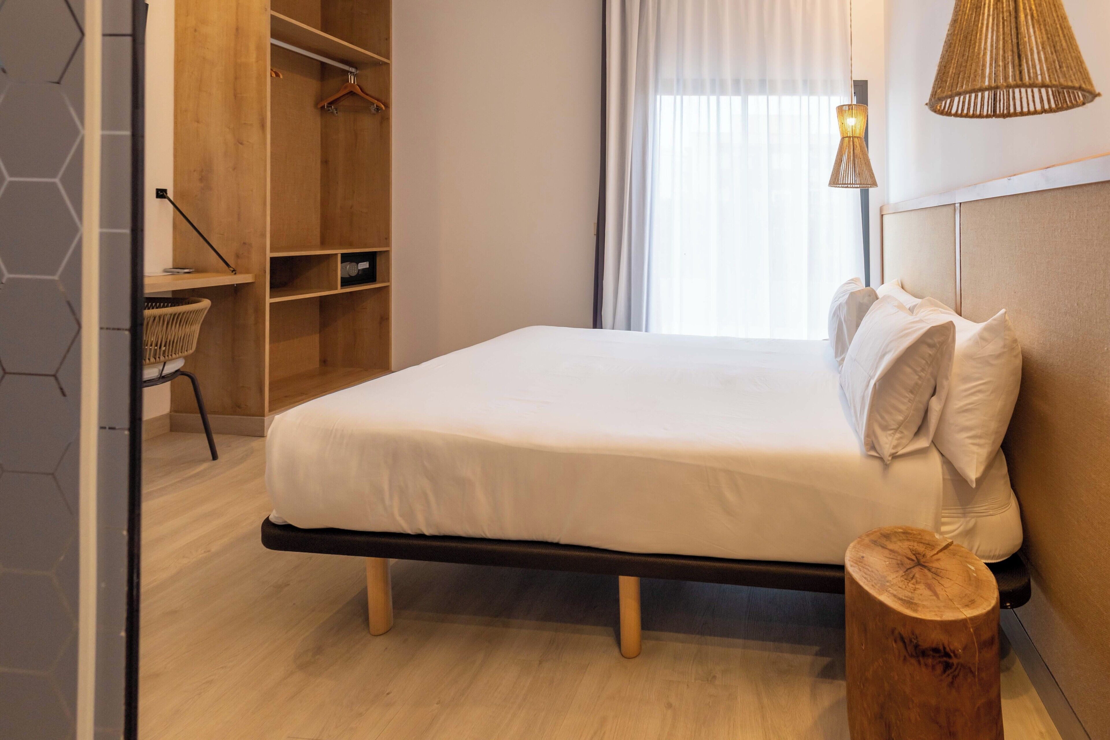 Un dormitorio moderno con cama, armario de madera y mesita de noche.