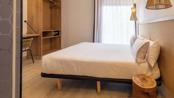 Un dormitorio moderno con cama, armario de madera y mesita de noche.