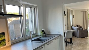 A modern kitchen with a large island, a dining area with a sofa, and a view through the window.