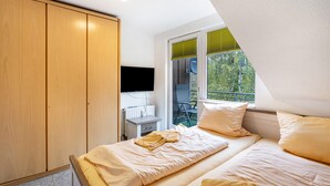 Un dormitorio con cama, armario, escritorio y ventana con persianas.